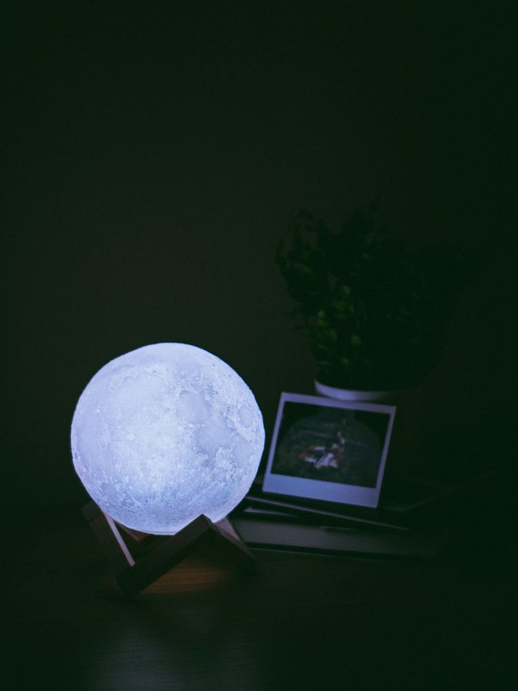 Lampă sferică texturată, iluminată din interior, pe suport de lemn